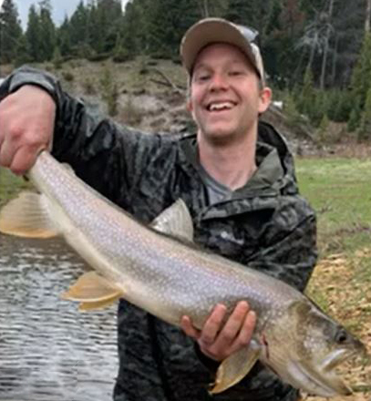 Timothy Borgogna standing in a river holding a trout. 